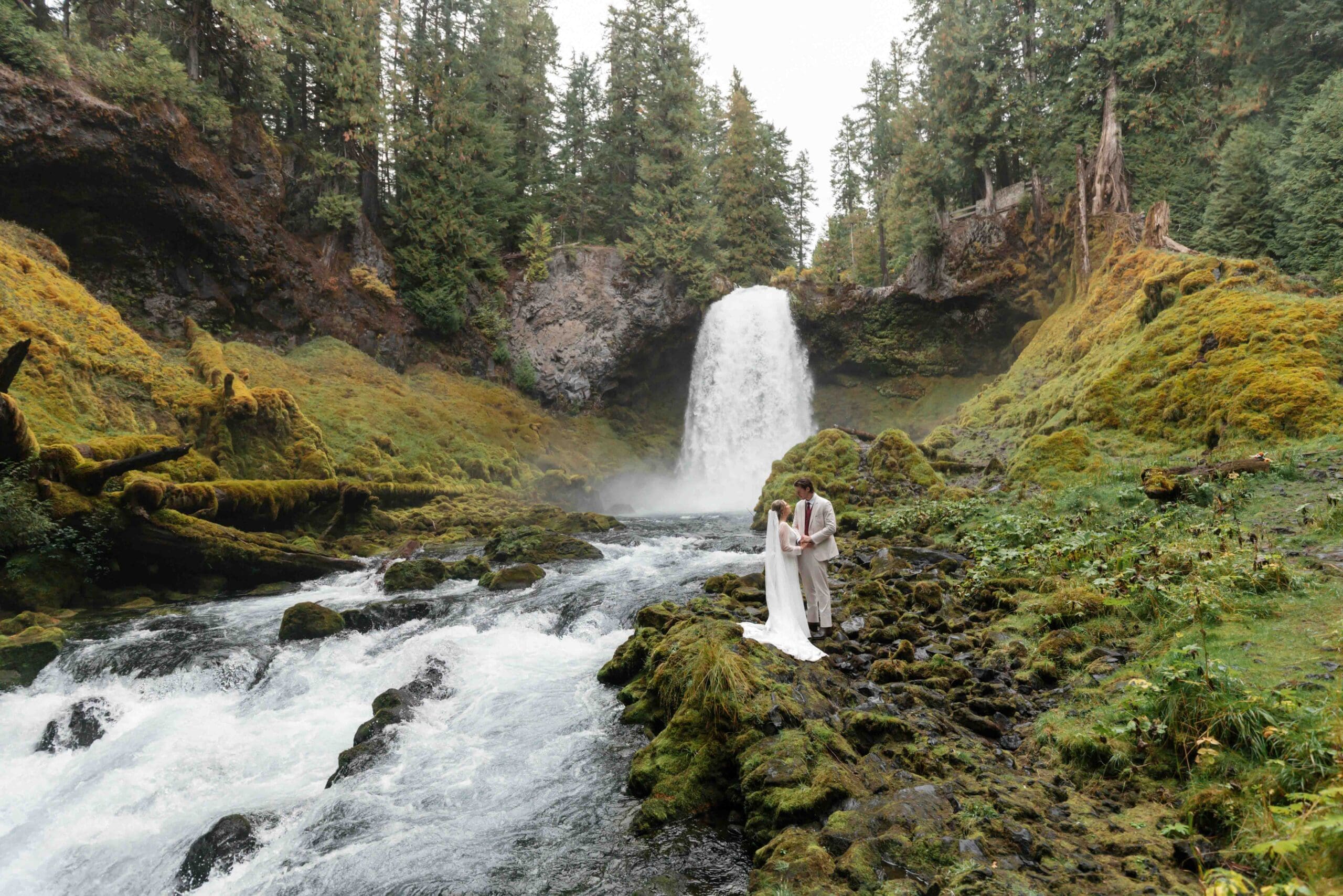 a wedding couple elope in front of a waterfall in Oregon