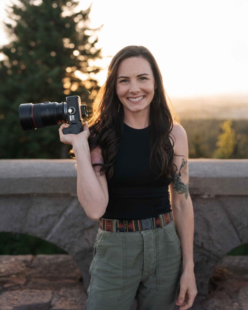 a elopement photographer smiles at the camera while holding her camera