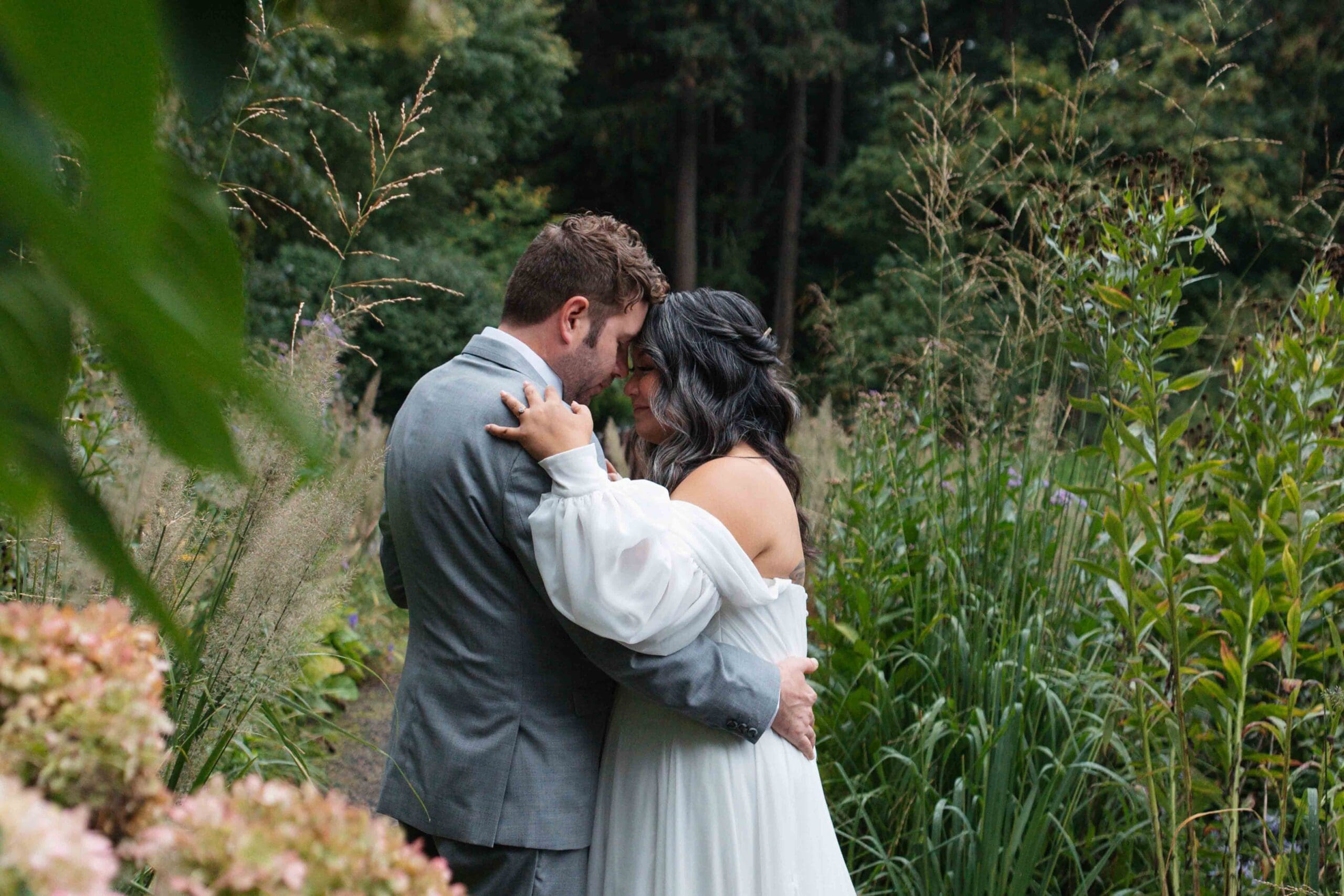 a wedding couple hug surrounded by flowers at leach botanical garden in portland oregon during their elopement