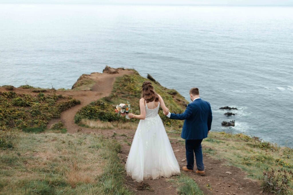 a wedding couple walk down to a viewpoint to exchange vows with the ocean as their backdrop