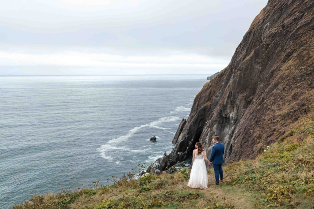 an elopement couple looks over the coast at an overlook