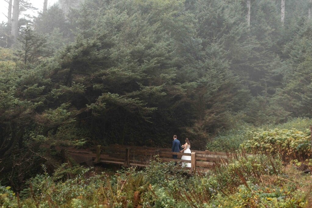 a couple walks across a bridge during their coastal elopement