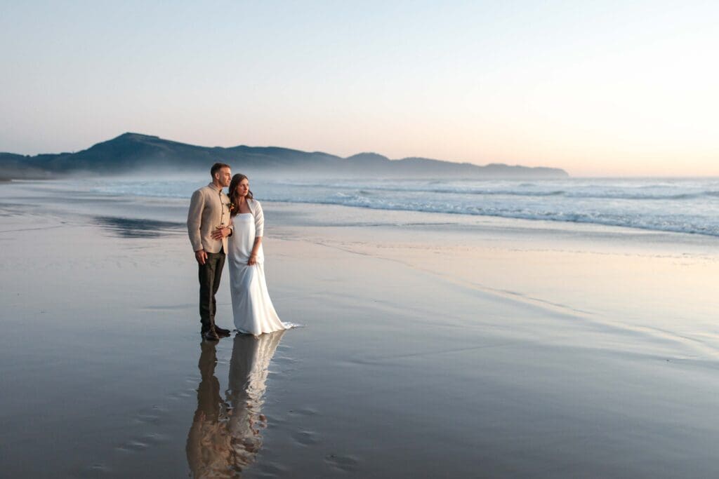 an elopement couple look out at the ocean during blue hour on the coast